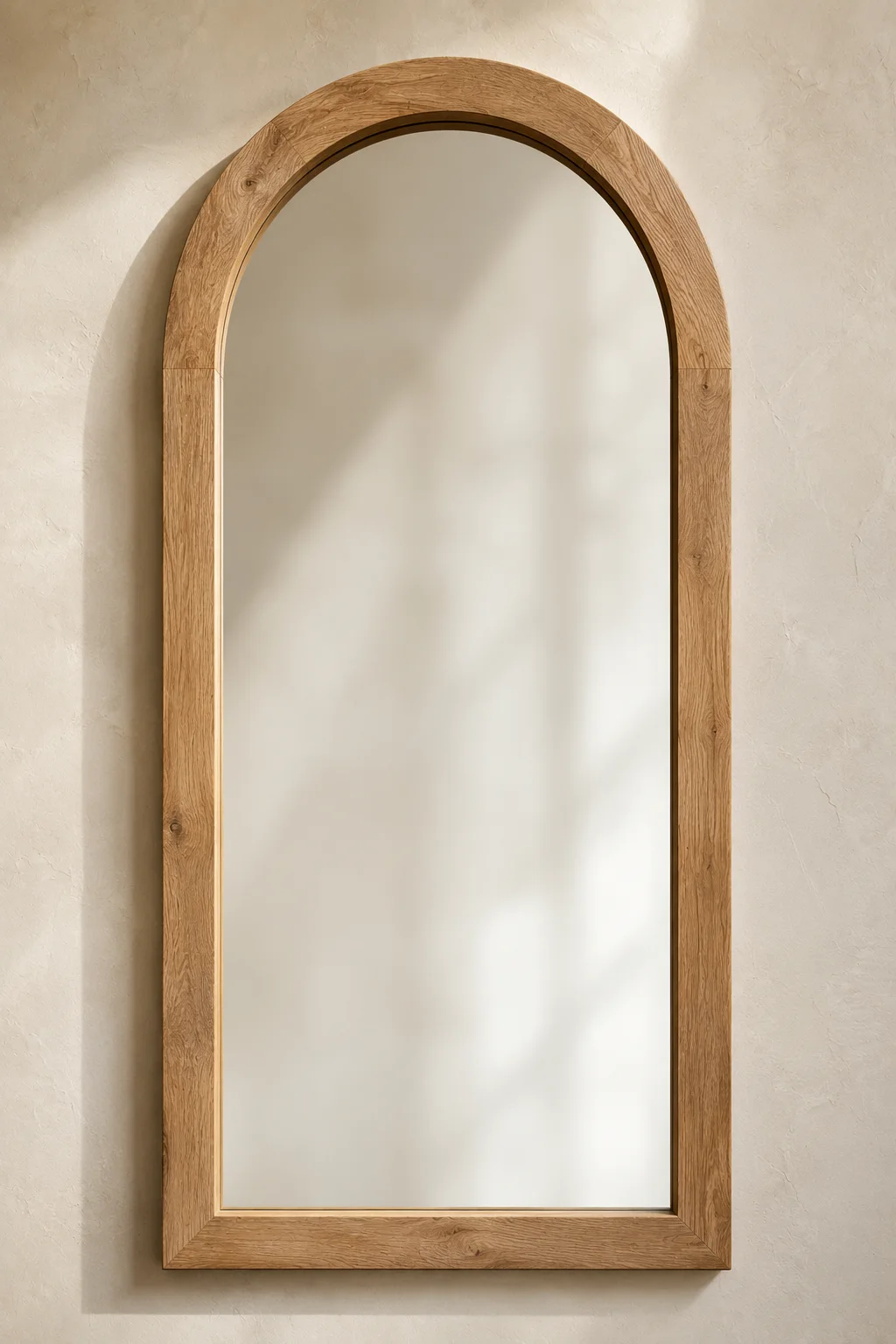 Elegant arched wood mirror frame featuring a tall handcrafted oak wall mirror with a graceful curved top, smooth natural wood grain, and seamless joinery. Mounted on a textured neutral plaster wall, this DIY mirror frame is perfect for modern farmhouse décor, entryway mirror inspiration, Mediterranean interiors, luxury bedroom mirrors, bathroom mirror upgrades, and timeless home decorating ideas.