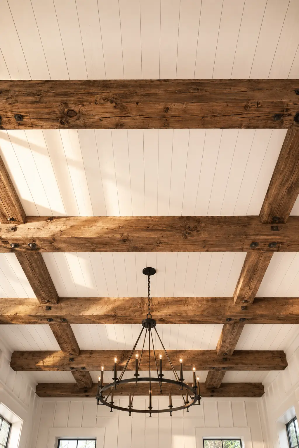 White shiplap ceiling with oversized reclaimed wood beam grid, exposed timber framework, black circular wagon wheel chandelier, warm rustic wood texture, symmetrical coffered beam ceiling, elegant farmhouse interior, luxury ceiling design, handcrafted wood beams, timeless architectural ceiling details, beautiful shiplap ceiling ideas with exposed beams