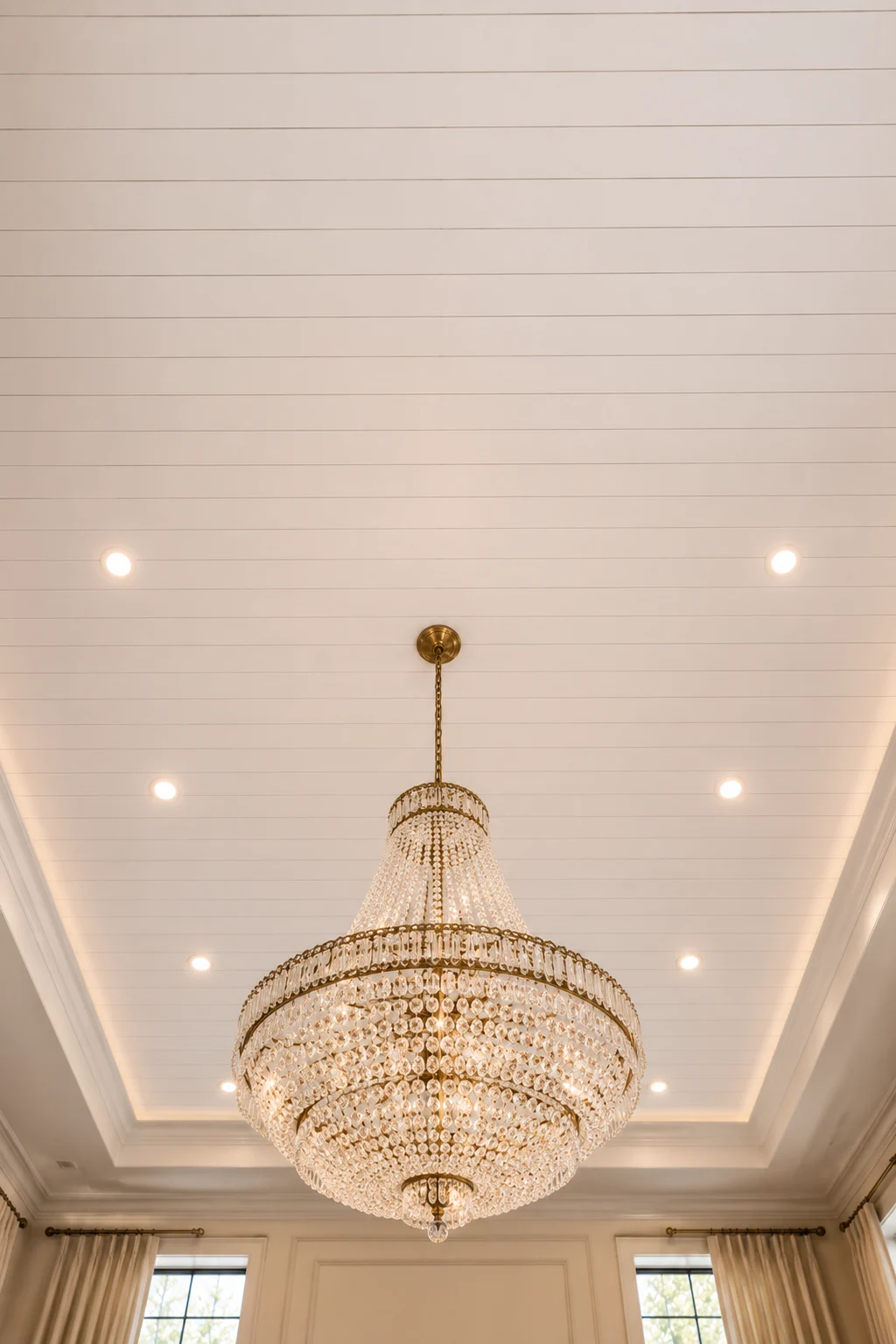 Luxury white shiplap tray ceiling featuring an oversized crystal chandelier, recessed ceiling lights, soft LED perimeter lighting, elegant white wood planks, glamorous classic interior, grand ceiling architecture, premium home ceiling inspiration, timeless luxury shiplap ceiling design with statement lighting