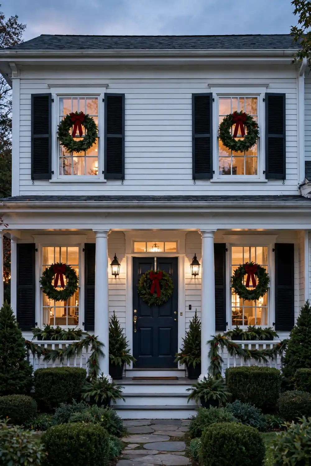 Matching evergreen wreaths with red bows on every front window of a house, classic christmas window decor ideas