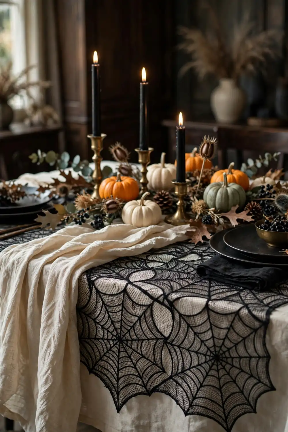 Spiderweb Lace Halloween Tablecloth Black lace spiderweb tablecloth layered over a cream cloth with candles and pumpkins on top, a romantic halloween table decor idea