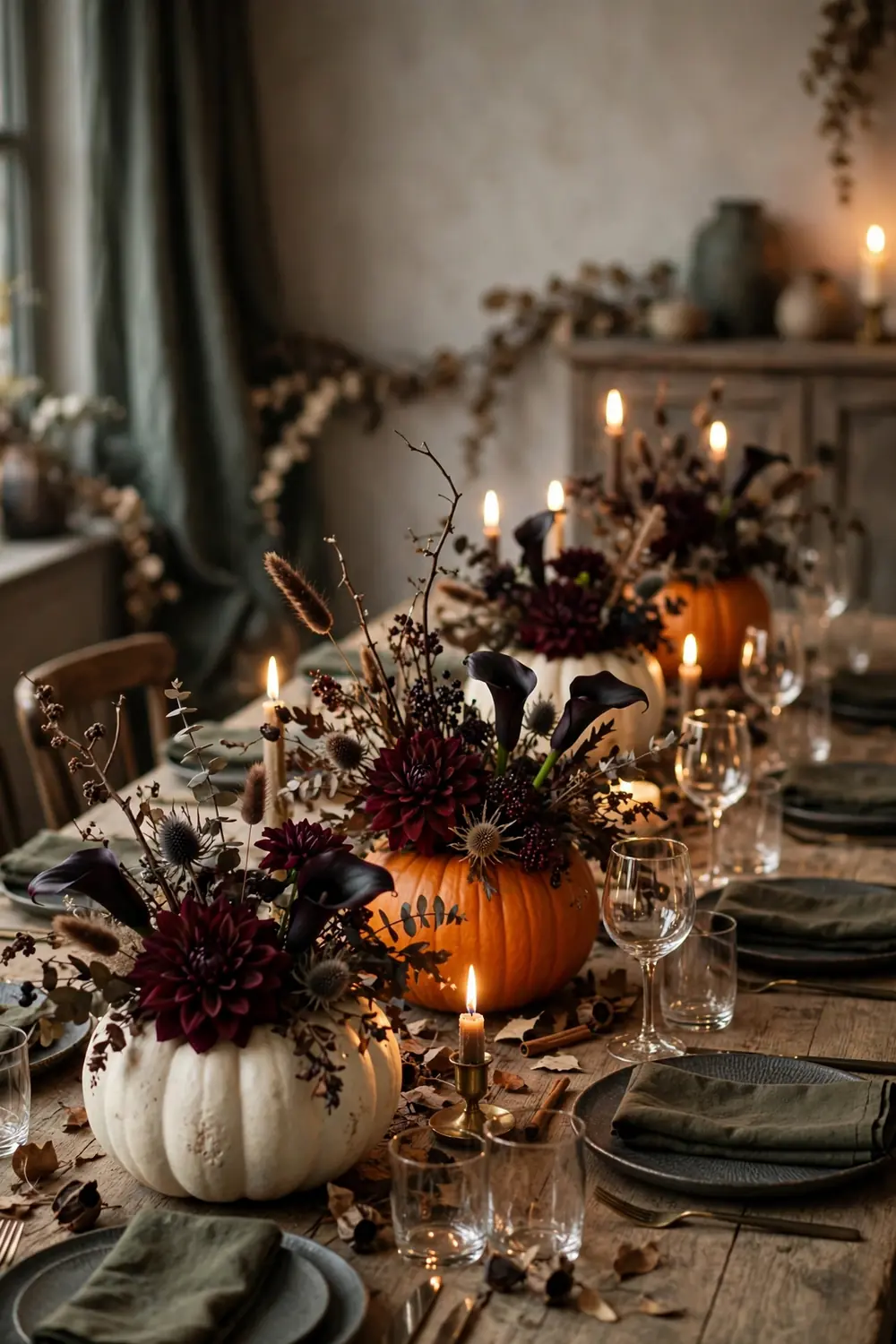 Hollowed Pumpkin Vases with Dark Florals Hollowed pumpkins used as vases with burgundy dahlias and dark florals on a candlelit table, a natural halloween table decor idea